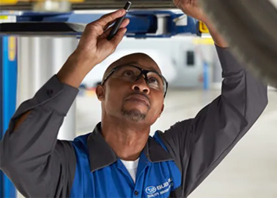 A Subaru technician under a Subaru vehicle.Schedule Service.